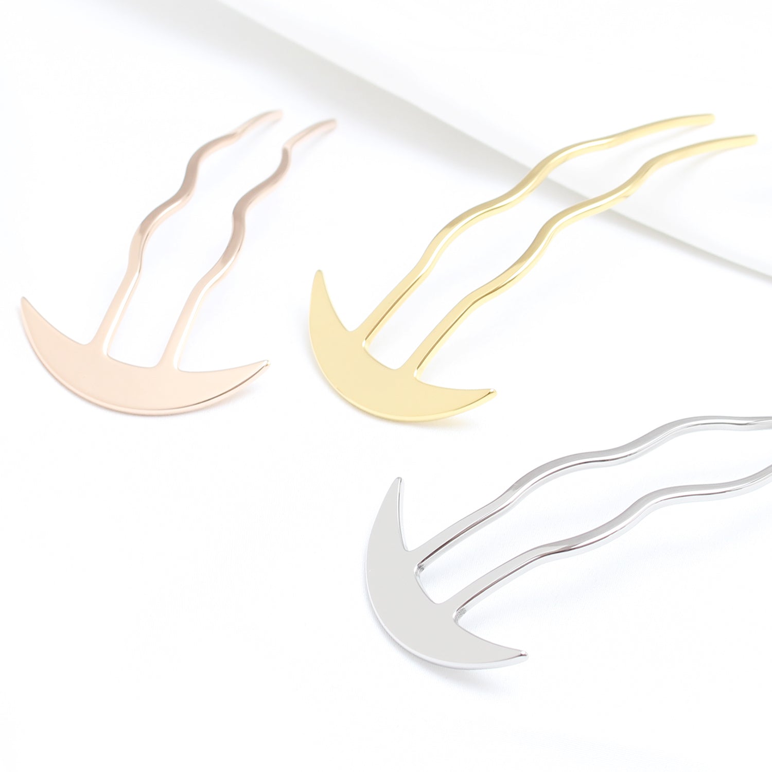 Three metallic hair clips in gold, silver, and rose gold on a white background