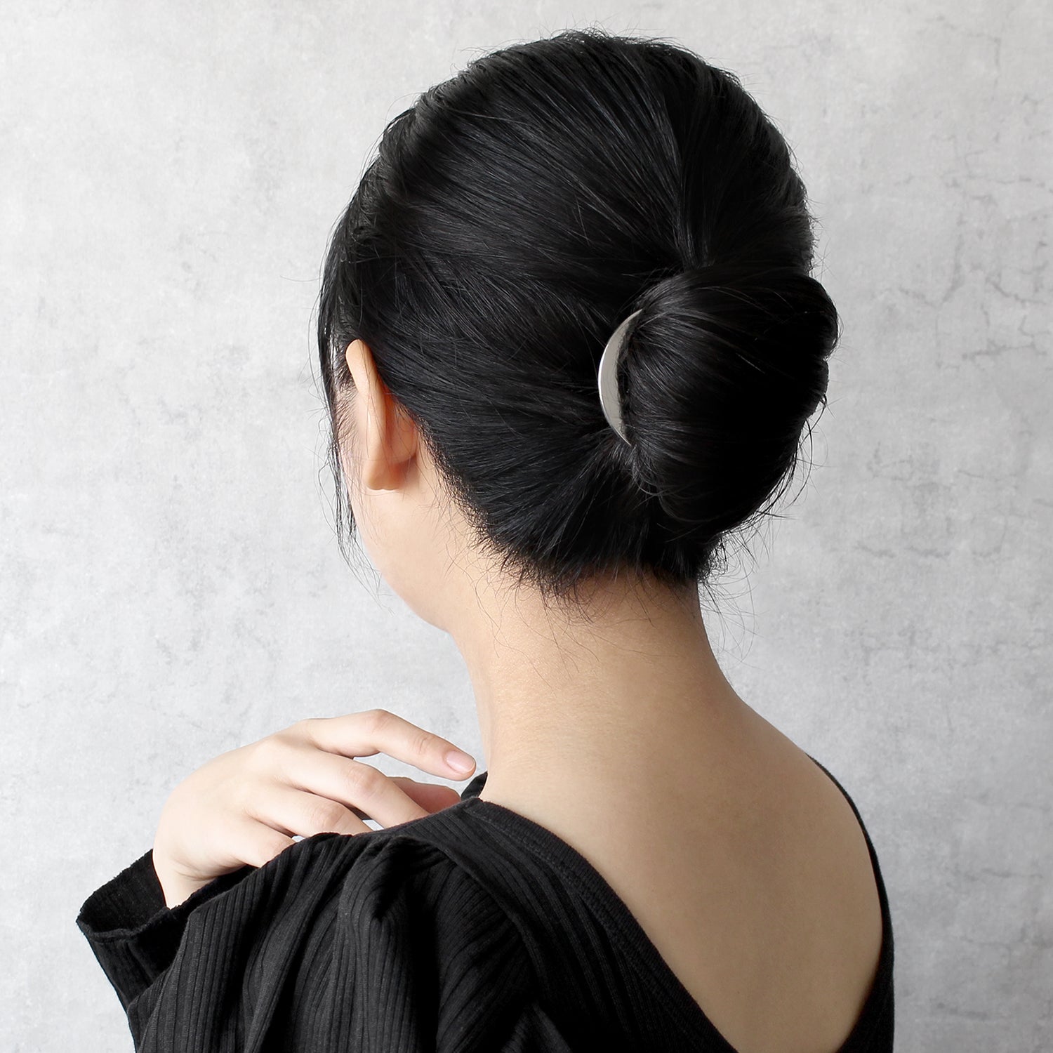 Person with a stylish black hair bun against a plain background wearing a silver arc liner kanzashi